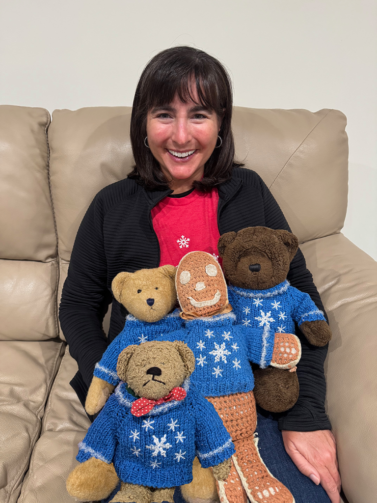 Julie seated on a couch with the characters the book was based on dressed in snowflake sweaters and sitting on her lap.